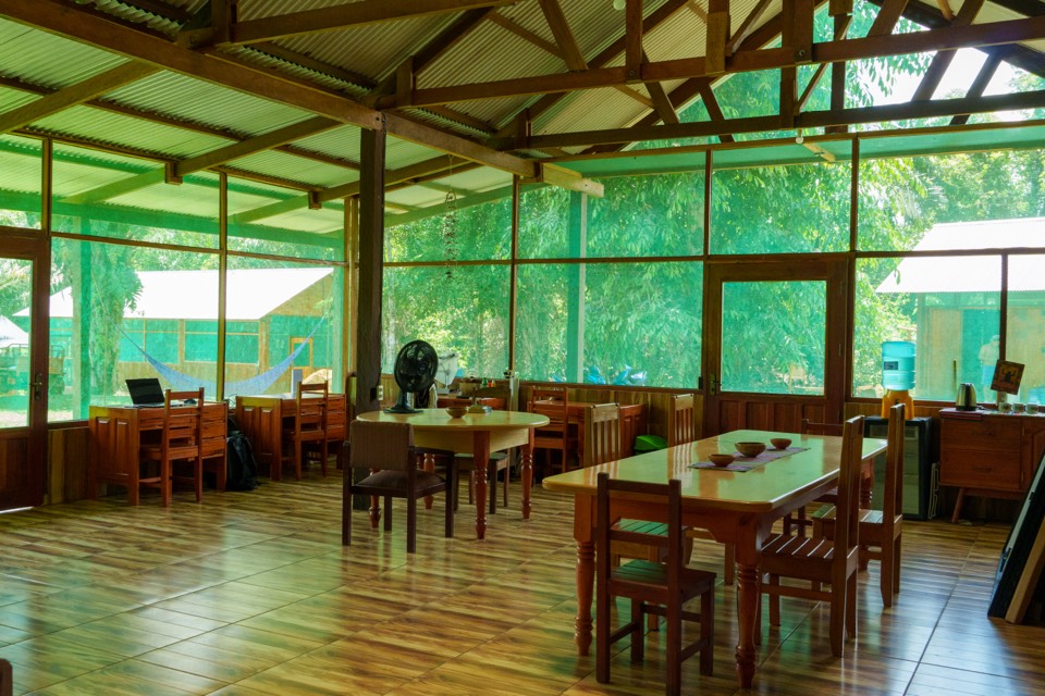 An empty dining hall with wooden tables and screened walls